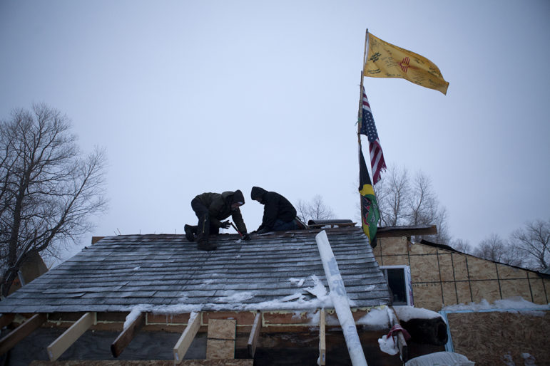 Brad Kallio and Linus Yellowhorse patch roofing on one of the many winter dwellings being constructed at the Oceti Sakowin Camp. 