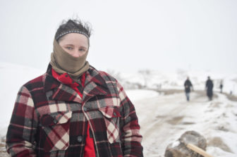 Crystal Houser of Oregon covers her face to stay warm at camp this winter. She encourages those around her to avoid conflict on a contentious bridge, where police and protesters have clashed in recent months.