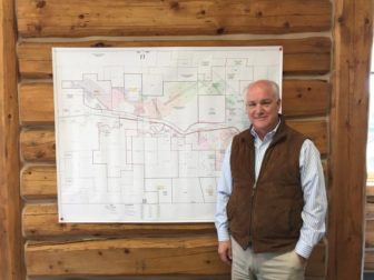 Randy Atkins standing in front of a layout of the Brook Mine in his Sheridan office