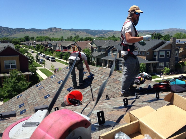Employees with Namaste Solar install mounting brackets for a new rooftop system in Boulder, Colorado.
