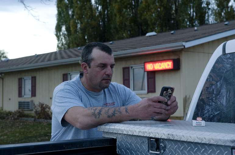 Bob Landerer, a crude oil truck driver from Pennsylvania now working in North Dakota, texting his wife back home. Landerer sleeps in his truck but showers and does laundry at the motel behind him. New Town, North Dakota. 
