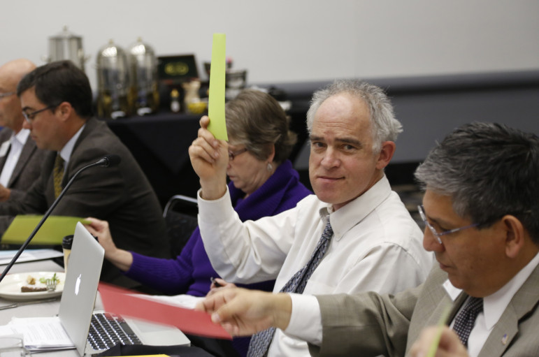 Task force member Will Toor holds up a green sheet to vote in favor of a policy recommendation during the group's February 3rd meeting. 