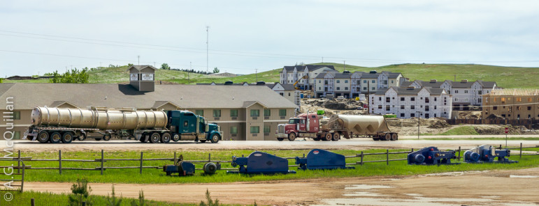 Oil trucks drive in front of new housing construction in Watford City, North Dakota.