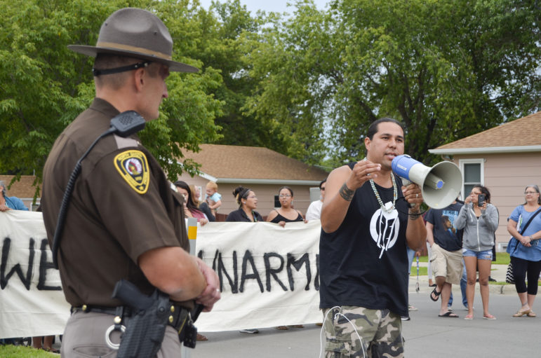 Dallas Goldtooth of the Indigenous Environmental Network voices his opposition to the Dakota Access Pipeline while law enforcement monitors the protest on the street in front of the North Dakota Capitol. Highway Patrol Capt. Bryan Niewind offered him a megaphone to amplify his voice.