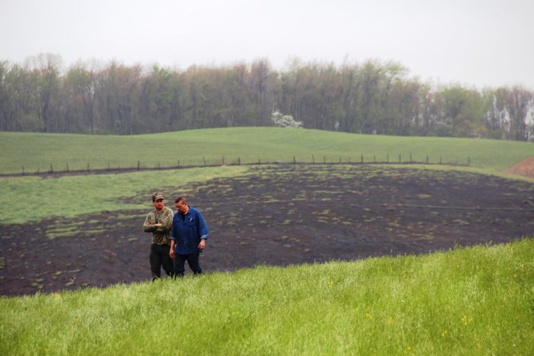 Two men walk the scene of a natural gas transmission line explosion in western Pennsylvania, April 29, 2016. The blast was so powerful it ripped a 12-foot crater into the landscape and burned a section of the field with a quarter-mile radius.