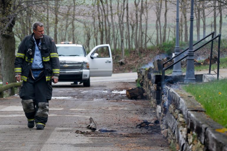 A first responder walks by smoldering wood and a burning retaining wall near a home following a natural gas explosion at a pipeline complex, on Friday, April 29, 2016, in Salem Township, Pa. The explosion caused flames to shoot above nearby treetops in the largely rural area, about 30 miles east of Pittsburgh, and prompted authorities to evacuate businesses nearby. 