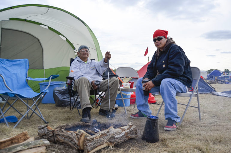 Quiltman Sahme, left, and son Tiwani sit outside their tent along the border of the Standing Rock Sioux Reservation in North Dakota where they're protesting the Dakota Access oil pipeline. They're from the Warm Springs Indian Reservation in Oregon, which is trying to prevent Nestle from bottling water from a nearby stream.